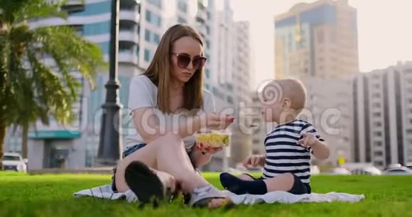 在公园的夏天妈妈用集装箱午餐喂孩子视频的预览图