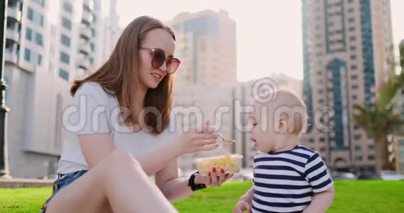 在公园的夏天妈妈用集装箱午餐喂孩子视频的预览图