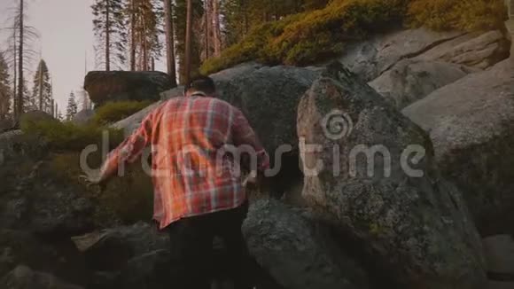 后景青年自由人徒步在美丽的日落时分在大岩石攀爬约塞米蒂国家公园森林慢动作视频的预览图