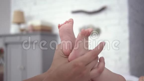 宝宝的双脚在妈妈关爱的手中紧紧地贴着妈妈刚出生的女孩在尿布上积极地移动着躺在换尿布的桌子上视频的预览图