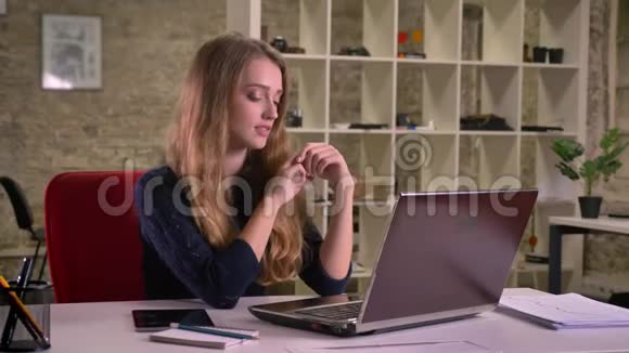 一幅漂亮的白种人金发女商人在办公室的笔记本电脑前慢慢跳舞的肖像视频的预览图