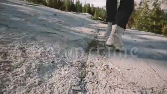 特写镜头跟随男性的双腿穿着白色沙漠鞋在史诗般的约塞米蒂森林岩石上奔跑和停下来视频的预览图