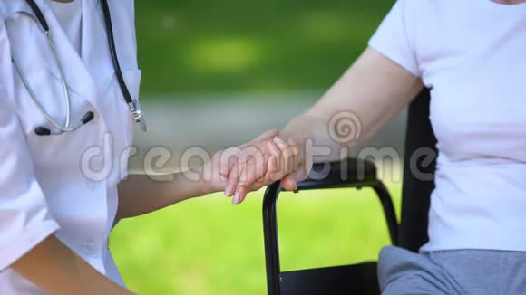 室外轮椅残疾老年妇女的女性治疗师手牵手视频的预览图