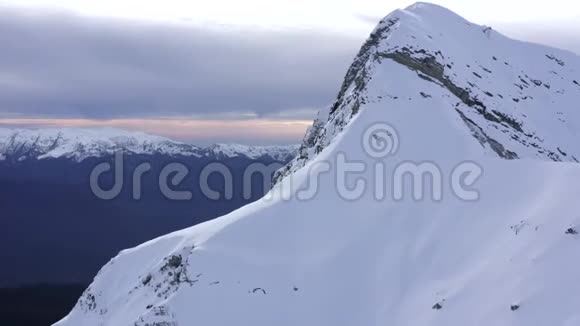 冬季的高山和多云天空中的雪峰上面的飞行无人机视频的预览图