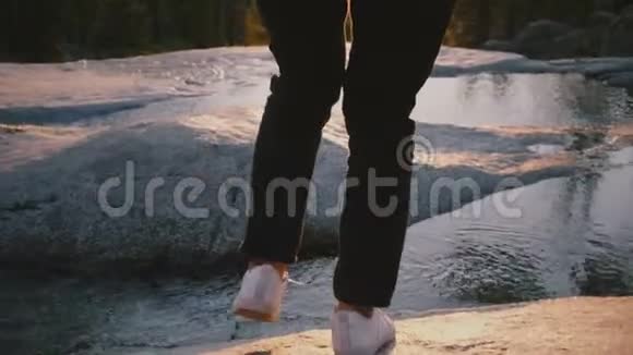 在约塞米蒂公园的一块岩石上女性的双腿小心地踩过一条美丽的小溪视频的预览图
