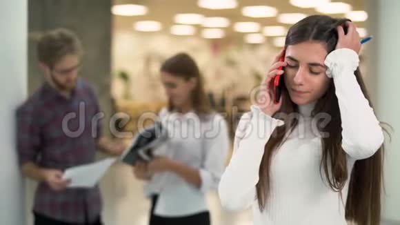 年轻女孩担心在工作场所通过电话交谈的肖像背景是聊天的人视频的预览图