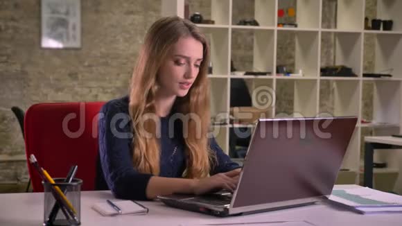 白种人金发碧眼的女商人在办公室里用手提电脑工作的肖像面临着麻烦和困惑视频的预览图