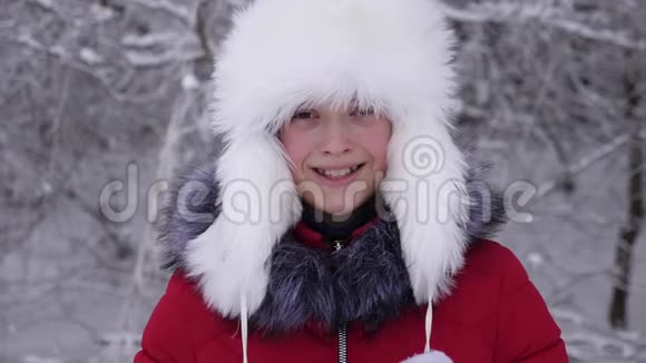 美丽的女孩在冬天下雪的公园里微笑白雪森林里快乐的少年视频的预览图