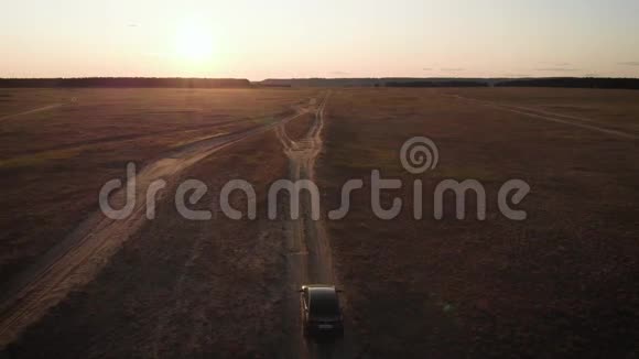 在美丽的日落中一辆汽车驶进远处的草地上汽车旅行概念视频的预览图