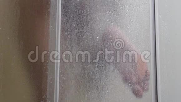 男人洗澡时动作缓慢水穿过身体湿人水穿过磨砂玻璃视频的预览图