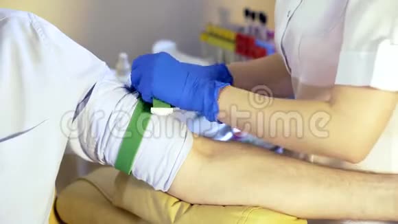 医疗诊所的一名护士在一名男性病人的手上扎止血带视频的预览图