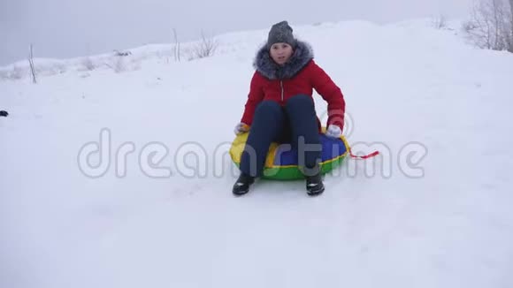 女孩骑着雪碟从高高的雪山和笑冬天孩子在雪橇上视频的预览图