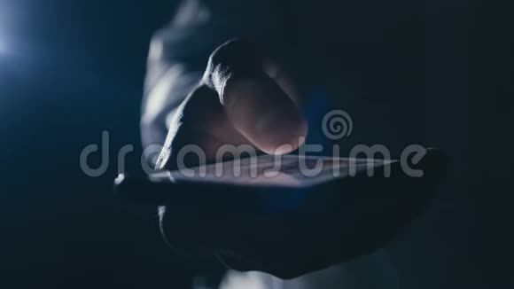 特写商人智能手机上的手指在黑暗中滚动视频的预览图
