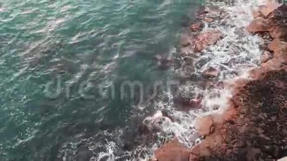 无人驾驶飞机观看海浪撞击岩石在刮风的日子里用大波浪拍摄岩石海岸的全景视频的预览图