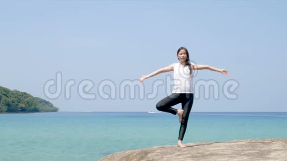 4K暑假期间一个女人站在一条腿上在海上的木桥上练习瑜伽视频的预览图