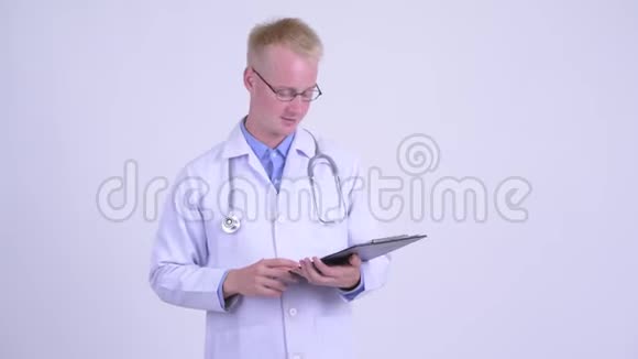 年轻的金发男医生边看剪贴板边说话视频的预览图