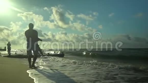 一位年轻的父亲和他的儿子沿着海滨散步阳光灿烂爸爸在旋转他的儿子家庭幸福视频的预览图