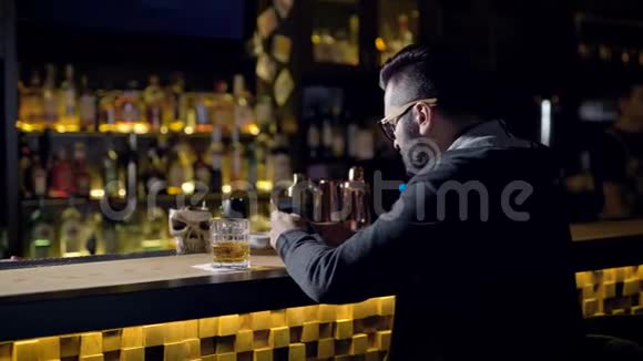 一个人拿着一杯威士忌静静地坐在酒吧里在网上聊天发出了一声巨响视频的预览图