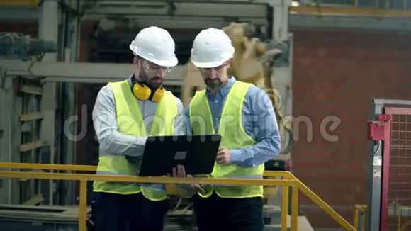 穿制服的工程师在工厂里用笔记本电脑工作视频的预览图