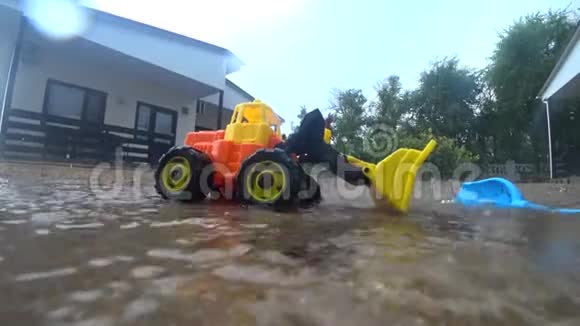 房子附近雨水下的沙子里的湿玩具视频的预览图