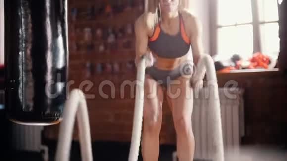 正在健身房训练的女运动员用绳索打击训练她的手视频的预览图