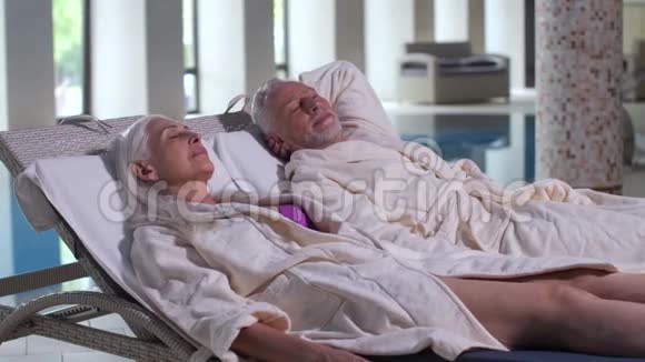 老年夫妇在酒店游泳池旁的日光浴床上放松视频的预览图