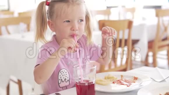 漂亮的小女孩在咖啡馆里吃薯条和番茄酱视频的预览图