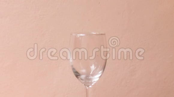 将红酒倒入粉红色背景的玻璃杯中视频的预览图