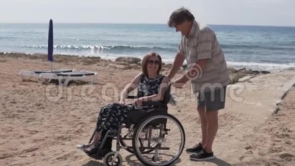 一位老人载着一位坐轮椅的妇女沿着大海视频的预览图
