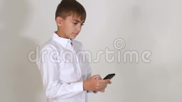 一个穿白色衬衫的小男孩的肖像白色背景上有一个电话视频的预览图