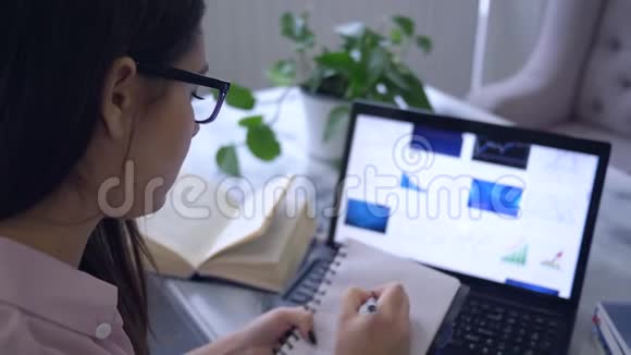在线讲座女学生在笔记本上画线图使用电脑坐在桌子上视频的预览图