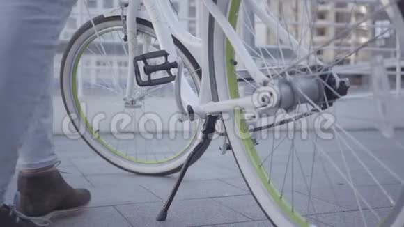 坐在自行车上在城市里骑自行车的年轻人的脚城市景观的背景休闲视频的预览图