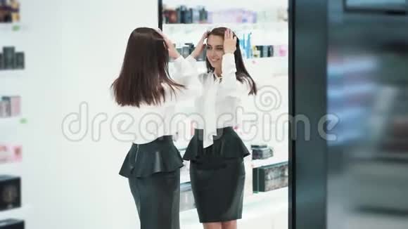 在化妆品店里漂亮的女人在镜子前打扮自己视频的预览图