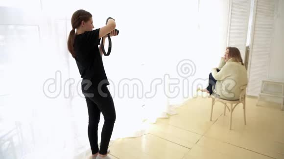 摄影师带模特坐在椅子上媒体模特被浪漫地放在靠近柔和光线窗户的椅子上视频的预览图