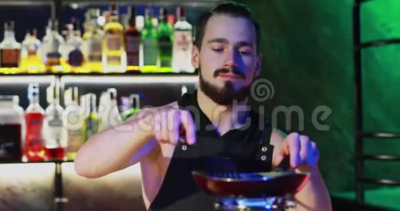 留着胡子的酒保在煤气炉上准备一杯美味的鸡尾酒视频的预览图