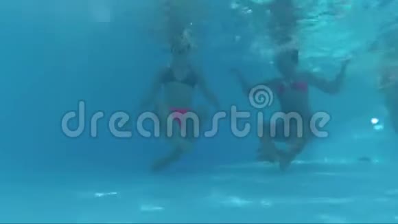 两个快乐的女孩坐在游泳池的底部玩得开心视频的预览图