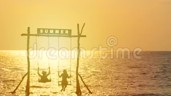 4K幸福夫妇的剪影喜欢在日落时间随着秋千在海上摇曳夏天的标志在上面暑假假期视频的预览图