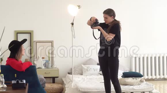 女人是摄影师和模特媒体摄影师把帽子系在漂亮的女模特身上视频的预览图