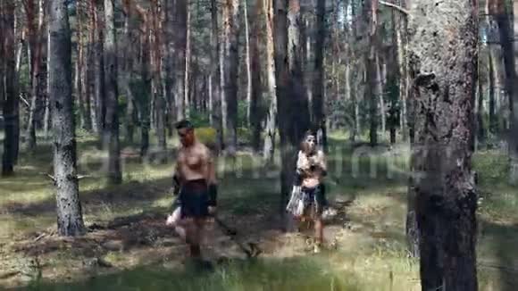 雄性和雌性野蛮猎人带着武器在森林里行走4k视频的预览图