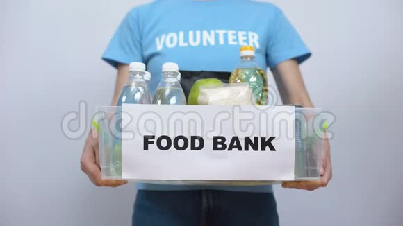 志愿者拿着食物库的容器手把食物放在盒子里帮助视频的预览图