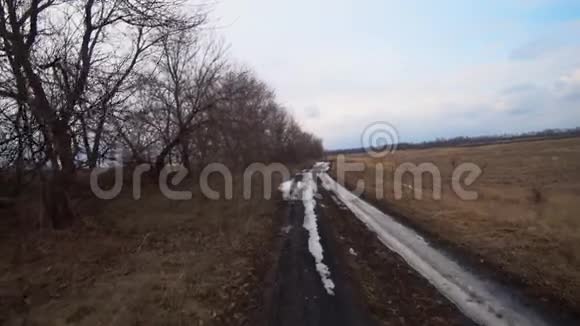 深秋越野车骑在田野和森林里的一条白雪皑皑的土路上视频的预览图