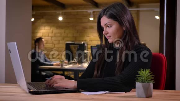 成人白种人黑发女商人在笔记本电脑上浏览并做笔记的特写照片视频的预览图