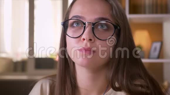 年轻貌美的白种人女学生戴着眼镜在公寓里看着摄像机视频的预览图