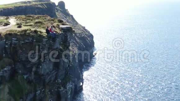 两个女孩坐在爱尔兰著名的摩赫悬崖边上视频的预览图
