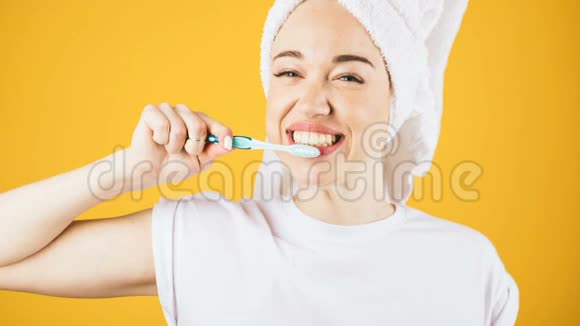 快乐刷牙女人穿白色t恤和黄色背景的毛巾停止动作延时录像视频的预览图