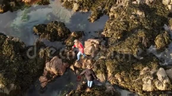 爱尔兰的两个女孩爬过马林海角的岩石海岸视频的预览图