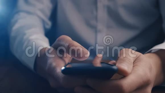 特写商人在黑暗中用手指在智能手机上滚动视频的预览图