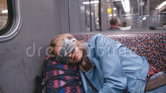 慢动作年轻漂亮的女孩在盲人的眼睛上睡着了地铁火车头放在背包上视频的预览图