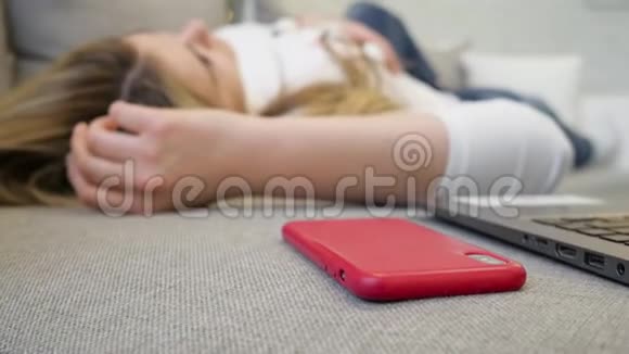 一个年轻女孩躺在沙发上接电话视频的预览图