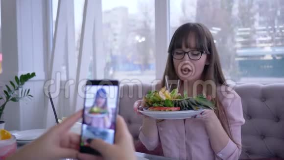健康的饮食和博客快乐的女孩戴着眼镜在盘子里摆着新鲜水果为女朋友拍照视频的预览图